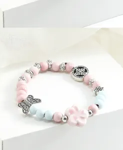 Inquadratura di dettaglio del bracciale di perle in ceramica con fiore e farfalla.