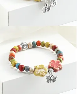 Dettaglio bracciale di perle in ceramica colorata con ciondolo a farfalla e fiore in argento.