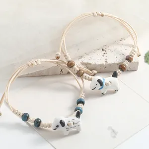 Ceramic dog charm woven bracelet detail, handmade cute pet style jewelry accessory close up.