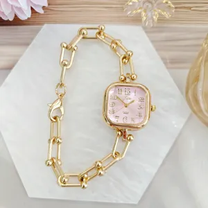 Close-up detail of a chic square pink dial women's chain watch with elegant gold finish.