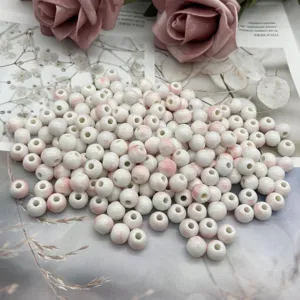 Detailed close-up of white ceramic loose beads with delicate pink glaze gradient.