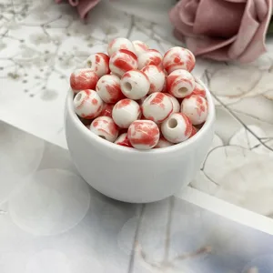 Ceramic splatter glaze beads detail shot, showing red and white porcelain texture and holes.