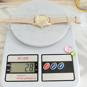 Gedetailleerd overzicht van het dames strass horloge met beige band op een digitale weegschaal.