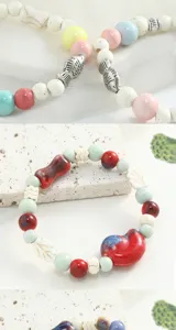 Detailed view of handmade ceramic beaded bracelet with cute fish and leaf charms, unique jewelry.
