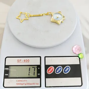 Detailed view of gold star keychain watch shown on scale, showcasing compact size and lightweight.