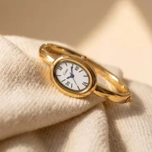 Nahaufnahme Detail der luxuriösen goldenen ovalen Armreif-Uhr mit römischen Ziffern.