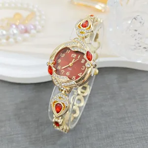 Detailed view of women gold watch, red dial, crystal rhinestone and gemstone decoration.