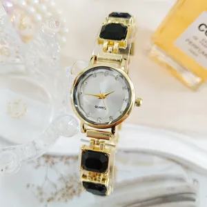 Vista detallada del reloj de cuarzo dorado con elegantes eslabones de pulsera de cristal negro.