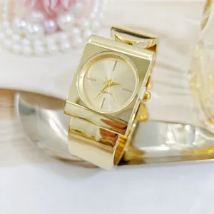 Gold square bangle watch for women, stylish minimalist cuff quartz wristwatch with metallic finish.