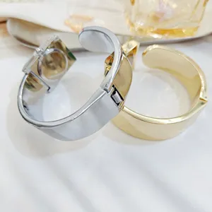 Detailed close-up view of stylish square dial bangle watches in silver and gold metal cuff designs.