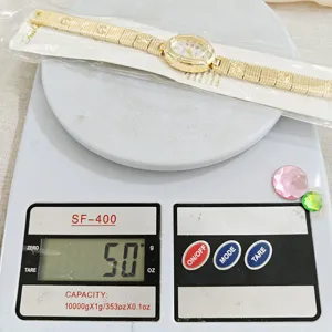 Vue détaillée de la montre quartz dorée avec des chiffres romains élégants et des strass brillants.