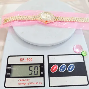 Vue détaillée de la montre pour femme en strass doré, vérification du poids et cadran.