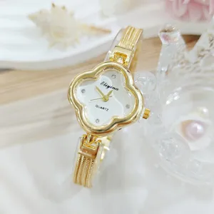 Primo piano del lussuoso orologio da donna al quarzo a trifoglio con strass e cinturino dorato.