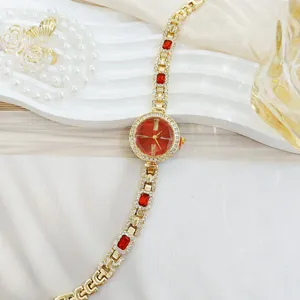 Luxus goldene Damenuhr mit roten Kristallen und funkelndem Diamantarmband fuer eleganten Stil.