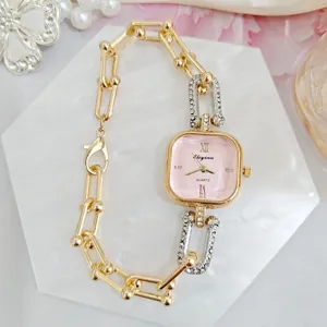 Detailed shot of trendy square pink dial women quartz watch with rhinestone chain strap.