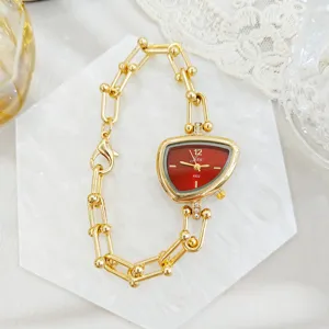 Modieus onregelmatig dameshorloge met rode wijzerplaat en gouden schakelarmband chic.