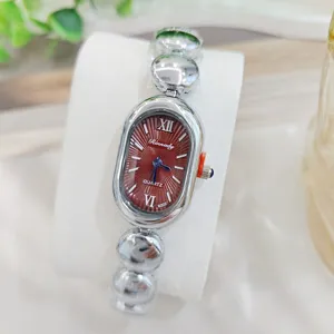 Detailansicht der Damen Vintage Quarzuhr, elegantes ovales rotes Zifferblatt mit silbernem Armband.