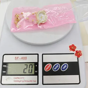 Detail shot of women quartz watch with pink beaded bracelet, weighing 20g on scale display.