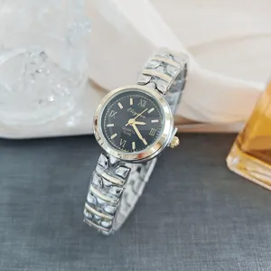 Close-up detail of women quartz watch with black dial, Roman numerals and two-tone steel strap.