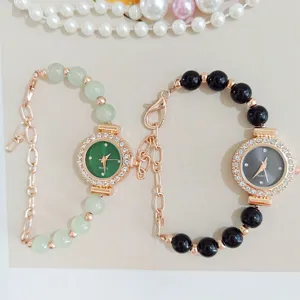 Detail view of women rhinestone quartz watch bracelet with green and black beaded straps.