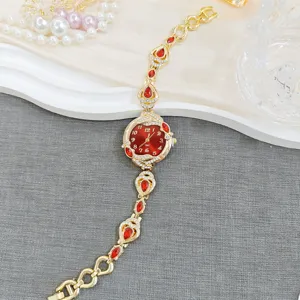 Vintage style women bracelet watch with red rhinestones and elegant gold chain design.