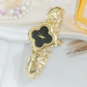 Exquisite close-up of luxury clover design women watch with elegant gold chain and black dial.