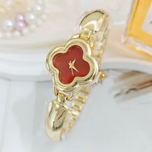 Detailed view of a luxury gold women watch with a striking red four-leaf clover dial.