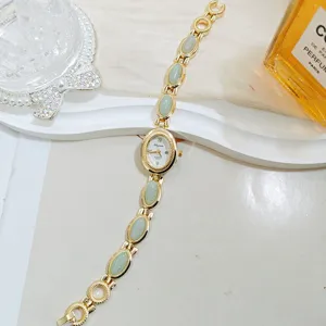 Vintage gold-tone women quartz watch with green oval stone links, elegant design.