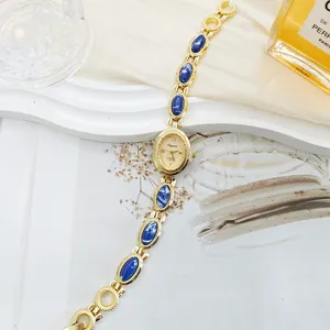 Vintage style gold women quartz watch detail featuring blue oval gemstone bracelet design.