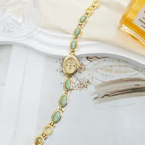 Vintage gold tone women quartz watch detailed view, featuring elegant green stone link bracelet.