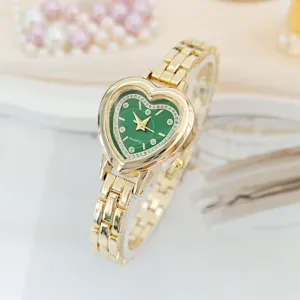 Primo piano dell'elegante orologio al quarzo dorato a cuore con quadrante verde e cinturino chic.