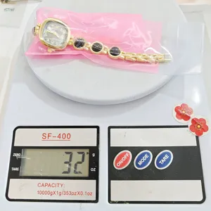 Reloj de cuarzo dorado con una elegante pulsera decorada con finas piedras negras.