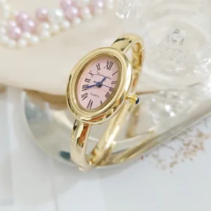 Retro oval quartz watch for women with pink dial Roman numerals and stylish gold bangle strap.