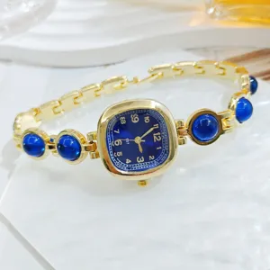 Elegante reloj de pulsera dorado para mujer con esfera cuadrada azul oscuro y piedras azules.