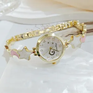 Close-up detail of luxury gold-tone women bracelet watch featuring star and moon charms.