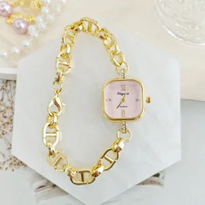 Detailaufnahme einer quadratischen rosafarbenen Quarzuhr mit goldenem Gliederarmband.