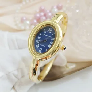Elegant gold bangle watch for women featuring an oval blue dial and classic Roman numerals.