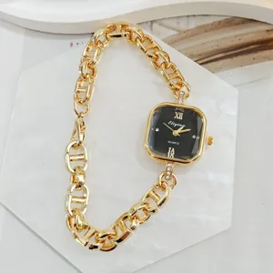 Detailansicht der goldenen Damenuhr mit quadratischem Zifferblatt und Kettengürtel.