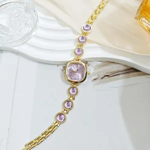 Detalle de primer plano de un elegante reloj de mujer dorado con pulsera de gema morada.