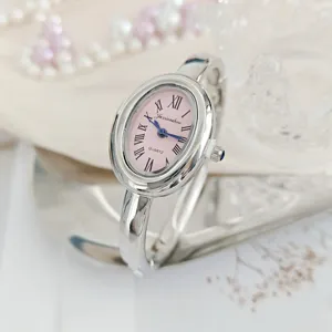 Vintage oval quartz bangle watch for women featuring a pink dial and Roman numerals.