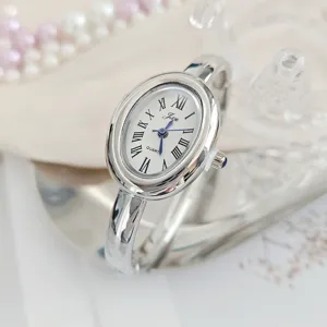 Detailed view of silver oval bangle quartz watch with elegant white Roman numeral dial.