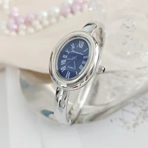 Silver oval bangle quartz watch for women with blue Roman dial, elegant daily wear.
