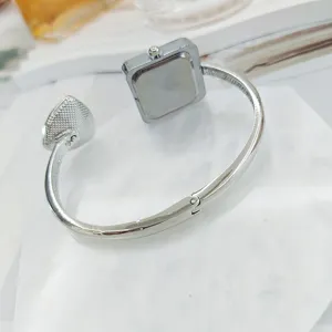 Detailaufnahme einer minimalistischen quadratischen Damen Armreif Uhr in offenem Silberton.