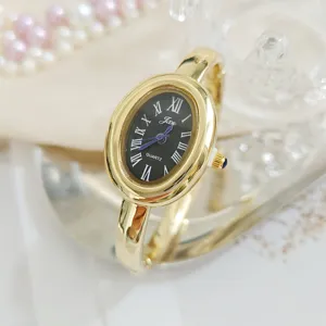 Retro oval gold women watch with black dial roman numerals and elegant bangle bracelet.