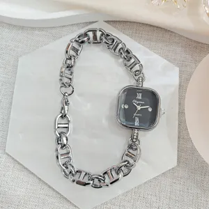 Nahaufnahme der quadratischen Quarzuhr mit klobigem Kettenarmband und funkelnden Kristalldetails.