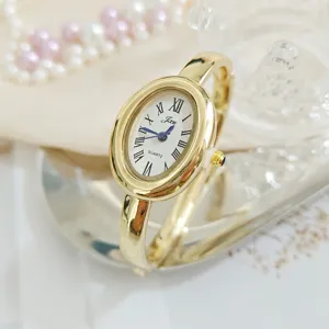 Vintage gold oval bangle watch for women with Roman numerals and quartz movement. Elegant.