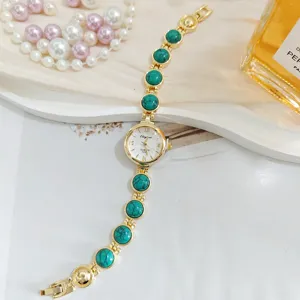Goldfarbene Damen Quarz Uhr Detail mit elegantem grünem Türkis Stein Armband Design.