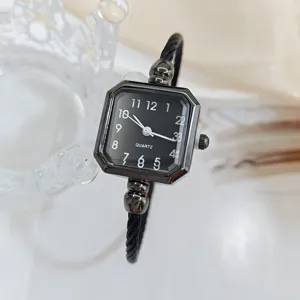 Vista dettagliata di un orologio al quarzo quadrato alla moda con quadrante nero e cinturino.