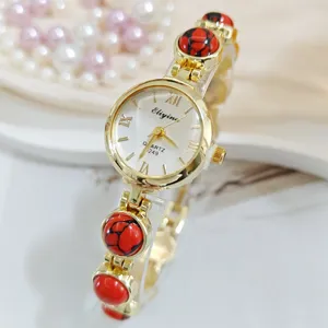 Detailansicht einer eleganten goldenen Damen-Quarzuhr mit roten Steineinlagen im Detail.