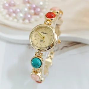 Zarte Damen Quarzarmbanduhr Detailansicht, elegantes Golddesign mit bunten Schmucksteineinlagen.